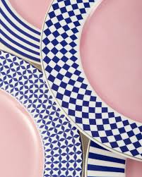 Abstract composition of blue and white patterned plates on a pink background.