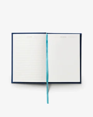 Open navy notebook with a turquoise ribbon bookmark; left page lined, right page blank.