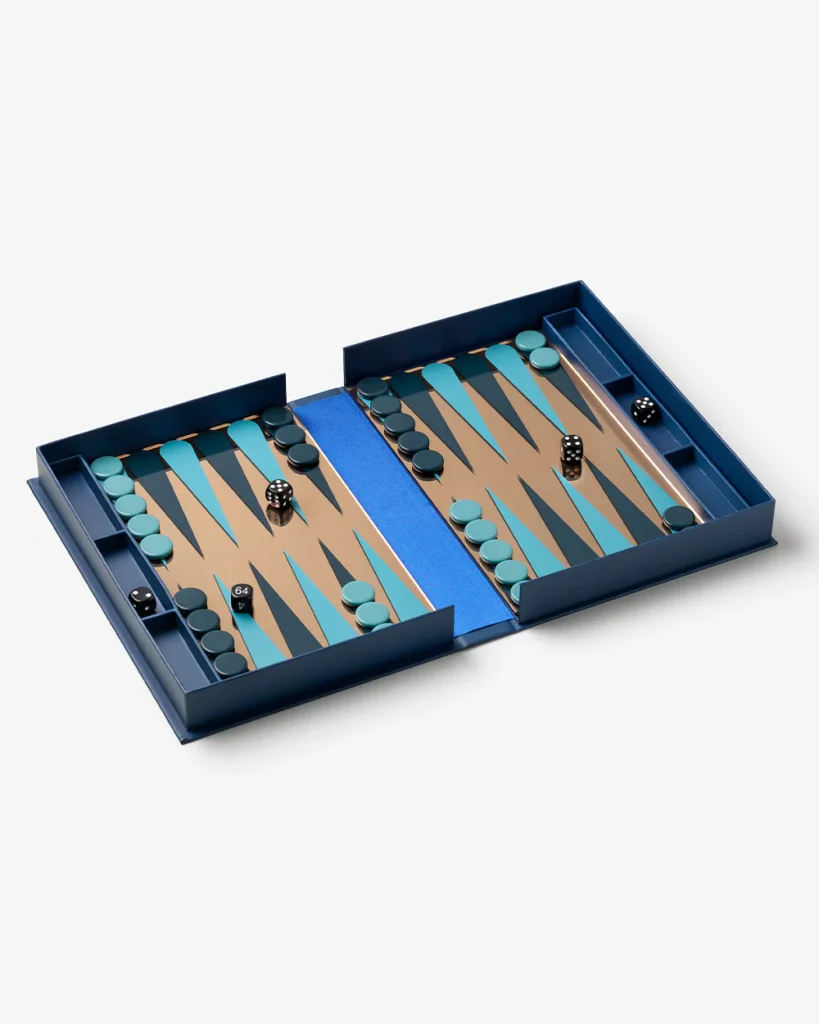 Open blue backgammon set with two playing boards, teal and dark pieces, dice, and a blue central divider on a light surface.