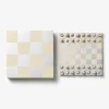 Two square boards side by side: the left is a beige-and-white checkered lid, the right shows a beige-and-white chessboard with metal pieces arranged along the top and bottom edges.