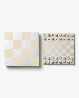 Two square boards side by side: the left is a beige-and-white checkered lid, the right shows a beige-and-white chessboard with metal pieces arranged along the top and bottom edges.