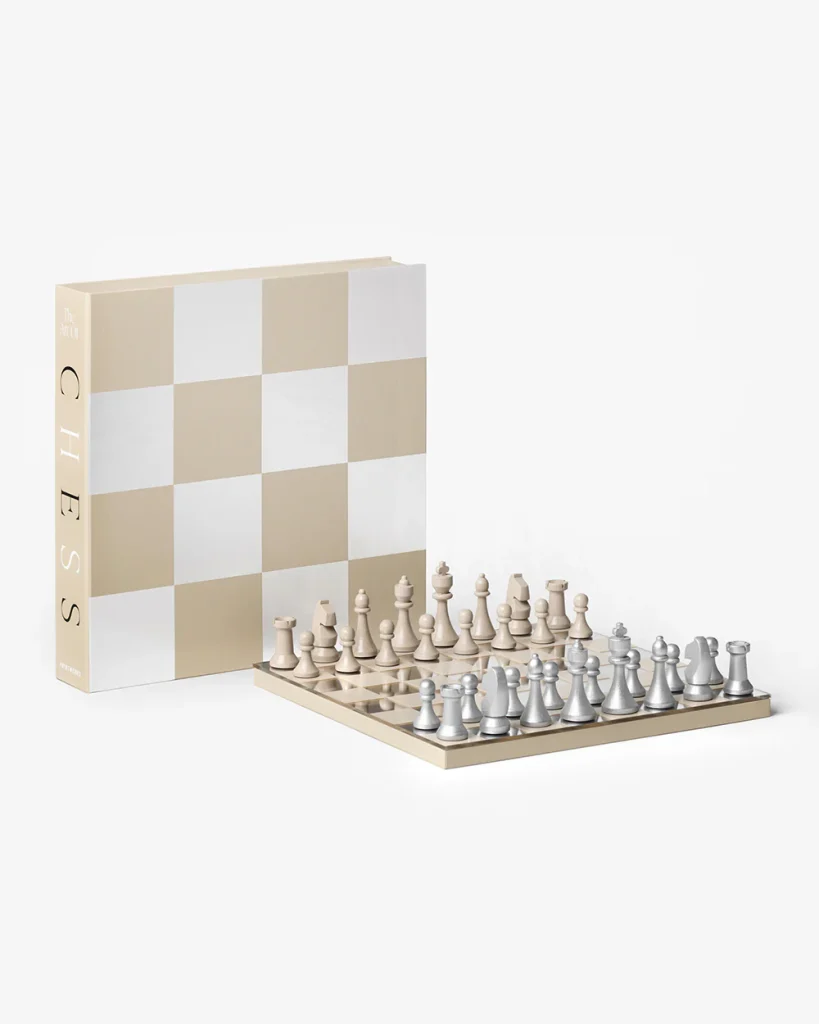 Beige and white chess set with pieces arranged on a board in front of a large beige-and-white checkered box.