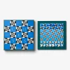 Two framed chess-themed artworks in blue tones: the left board shows the word CHESS in large letters on a geometric pattern, the right board displays a blue and white checked grid with pieces.