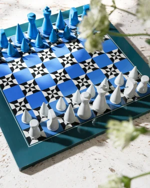 Blue and white chessboard with matching blue and white pieces arranged on a teal tray outdoors on a light stone surface.