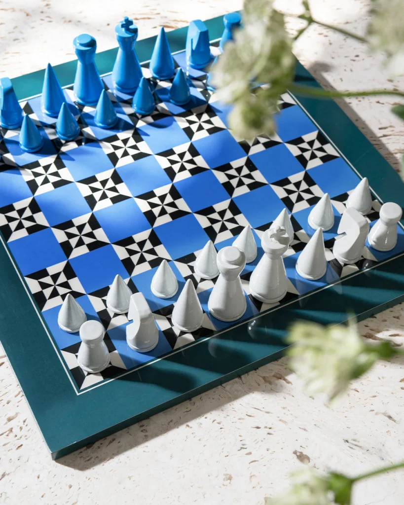 Blue and white chessboard with matching blue and white pieces arranged on a teal tray outdoors on a light stone surface.