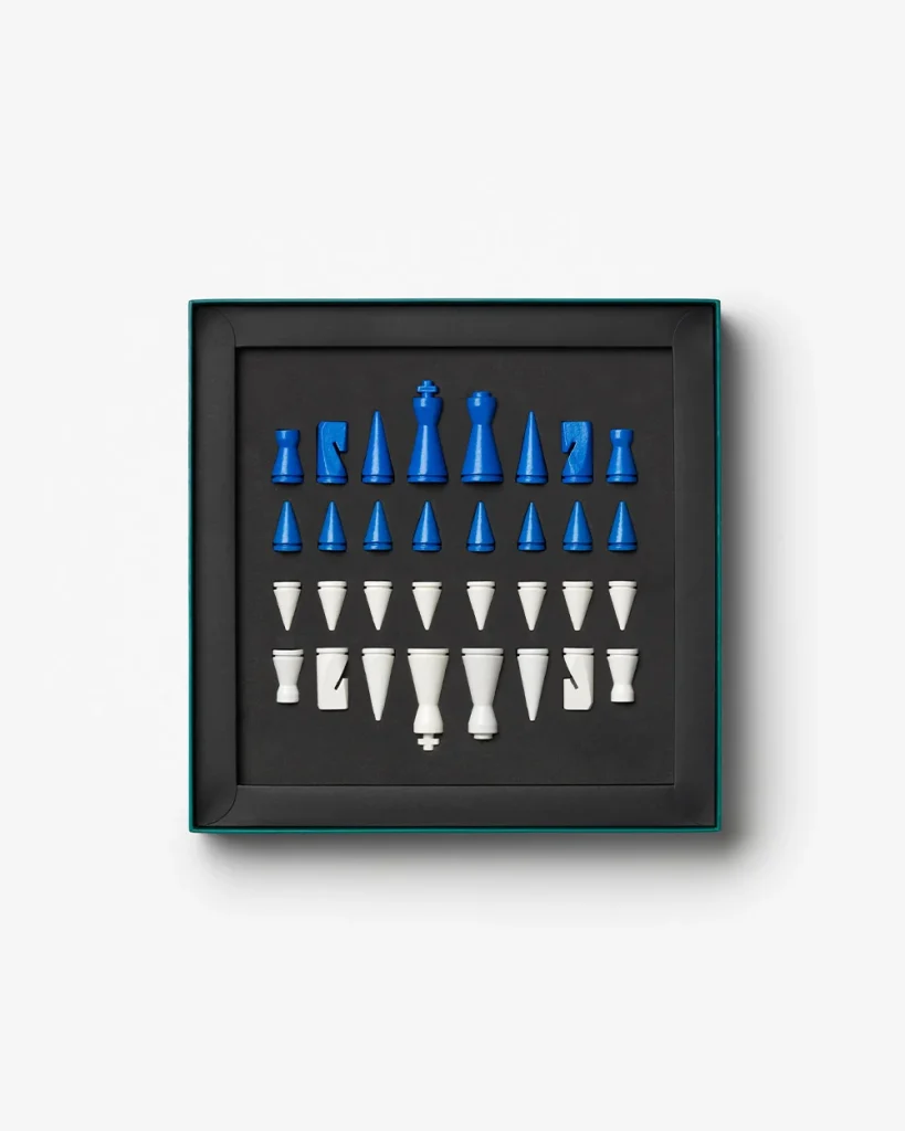 Boxed set of blue and white chess pieces arranged in rows on a black tray inside a dark box, viewed from above