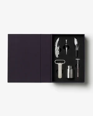Open dark purple gift box revealing a stainless steel wine accessory set in foam: corkscrew/lever, foil cutter, pourer, stopper, keeper/vent, and a thermometer.