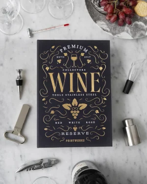 Dark blue wine book with gold lettering on a marble table, surrounded by wine accessories and a grape plate in the corner.