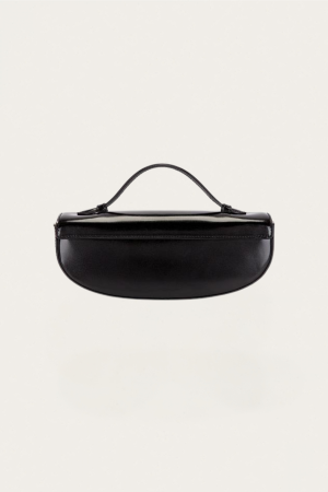 Black patent-leather clutch with a curved, short handle on a light background, centered in frame.