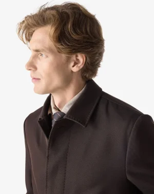 Side view of a man wearing a dark brown coat with a light scarf, facing left.