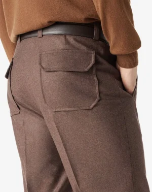 Back view of brown tailored trousers with a flap pocket and a black belt looped through the waistband.