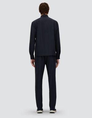 Back view of a person wearing a dark navy two-piece loungewear set (jacket and pants) with white-soled sneakers