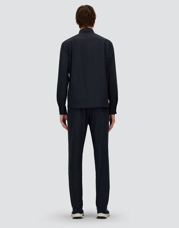 Back view of a person wearing a dark navy two-piece loungewear set (jacket and pants) with white-soled sneakers