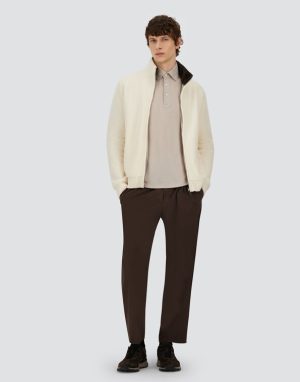 Model wearing a cream zip cardigan over a beige polo and dark brown trousers with brown sneakers, standing casually against a light background.