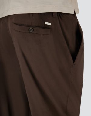 Brown trousers shown from the back with a single welt pocket and dark button.