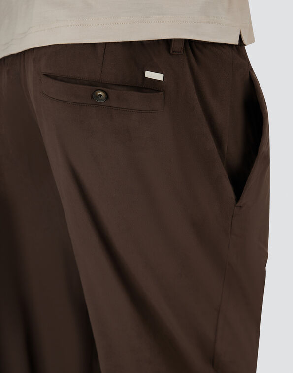 Brown trousers shown from the back with a single welt pocket and dark button.