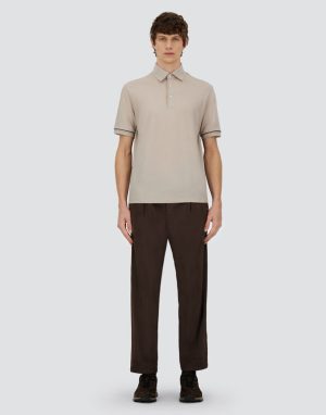Front-facing male model wearing a beige polo shirt and dark brown pants against a neutral backdrop, showcasing a casual outfit.