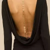 IMG_2555 - New Trend Back view of a person wearing a black open-back dress with a gold circular-link necklace draping down the spine.