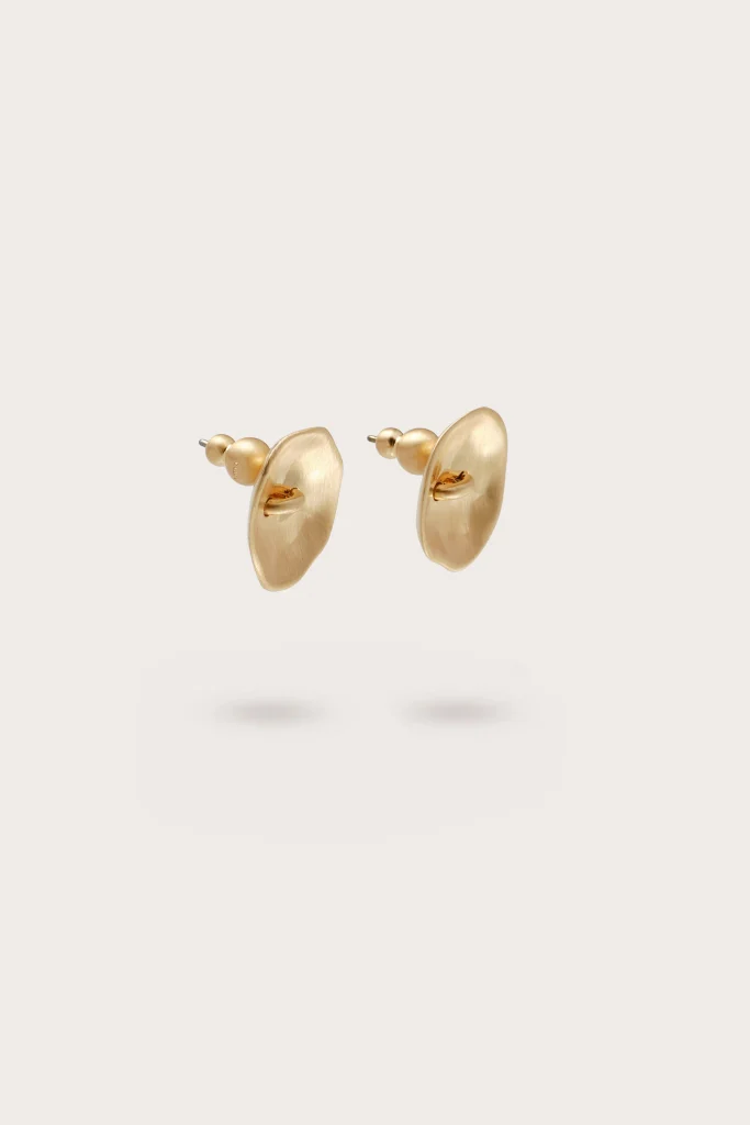 Gold-toned drop earrings with oval front discs and small bead backing, floating above a pale background.