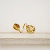 Gold bracelet with two large leaf-shaped charms resting on a light display pedestal.