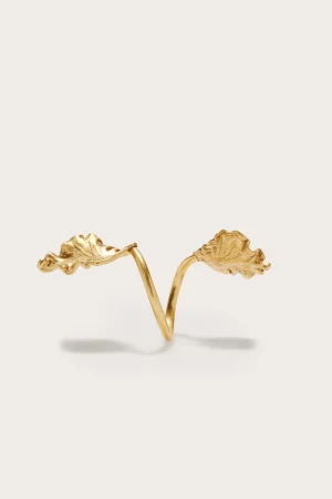 Gold ring with two leaf-shaped branches forming an open, nature-inspired design on a light backdrop