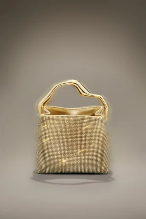 Gold-toned handbag with a sculpted metallic handle and a studded, shimmering surface against a neutral gray backdrop
