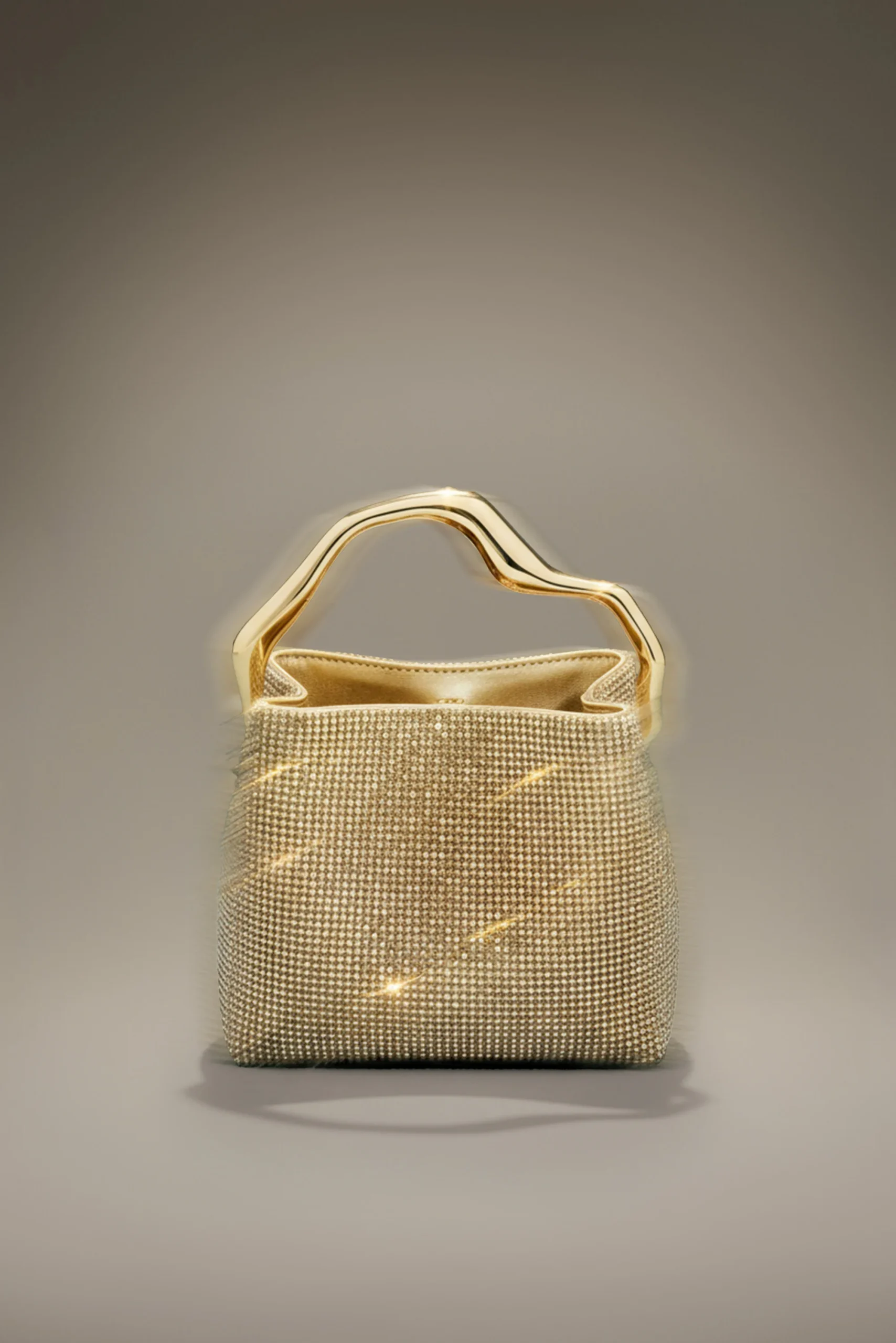 IMG_2606 - New Trend Gold-toned handbag with a sculpted metallic handle and a studded, shimmering surface against a neutral gray backdrop