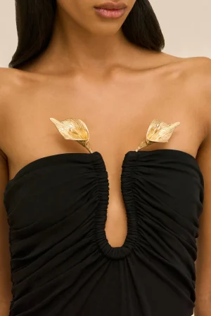 Close-up of a woman wearing a black strapless outfit with gold leaf pasties over the chest area.