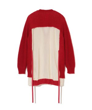 Back view of a bright red knitted sweater worn over a cream vertical-striped dress with pink trim and ribbons on the sides.