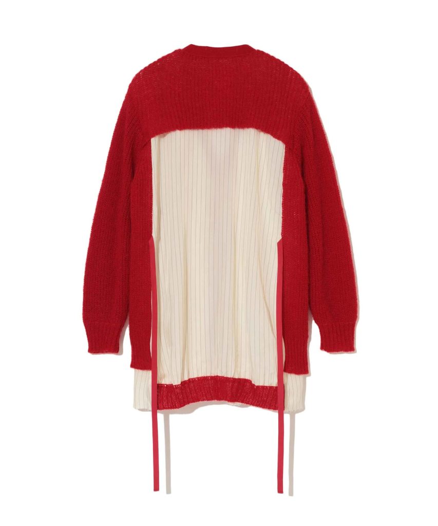 Back view of a bright red knitted sweater worn over a cream vertical-striped dress with pink trim and ribbons on the sides.