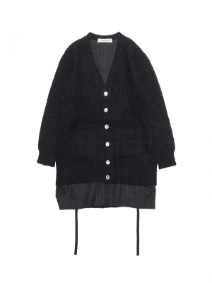 Black textured cardigan with white-button front over a dark pinstriped shirt peeking from the bottom, layered look