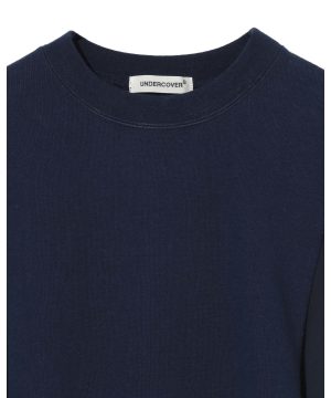 Close-up of a navy blue crew-neck T-shirt showing a white tag that reads UNDERCOVER at the back of the neck.