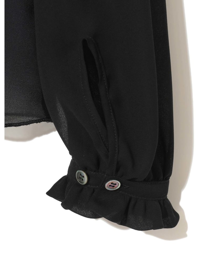 Close-up of a black garment sleeve with a gathered cuff and two buttons, showing a ruffled edge.