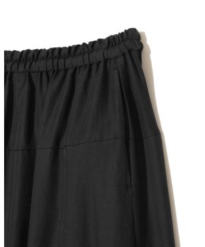 Close-up of black pants with a gathered elastic waistband (smocked) across the top edge of the garment.