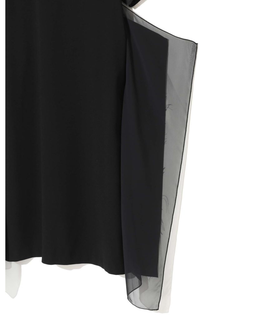 Close-up of a black garment with a sheer gray overlay along the right edge. The contrast shows a layered fabric detail.