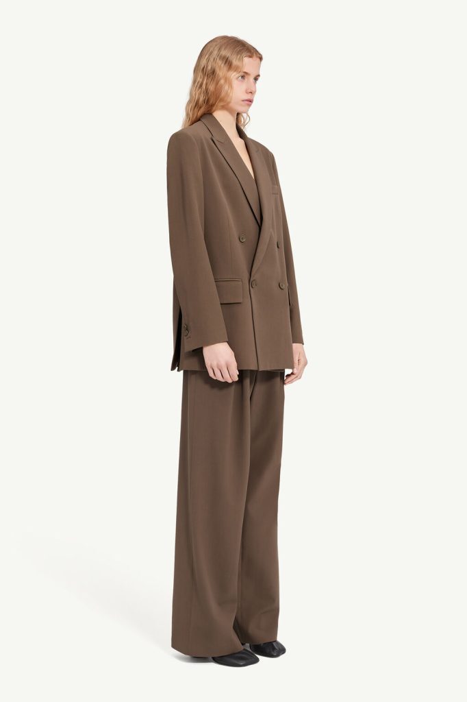 Model wearing a brown oversized double-breasted blazer with matching wide-leg trousers against a light backdrop, full-body view