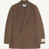Brown double-breasted blazer with peaked lapels, four buttons, and two front flap pockets on a light background.