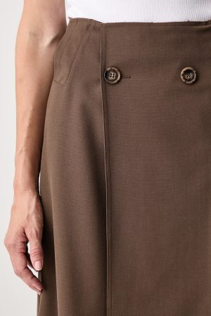 Close-up of a brown high-waisted skirt with two tortoiseshell buttons and a vertical seam, paired with a white top.