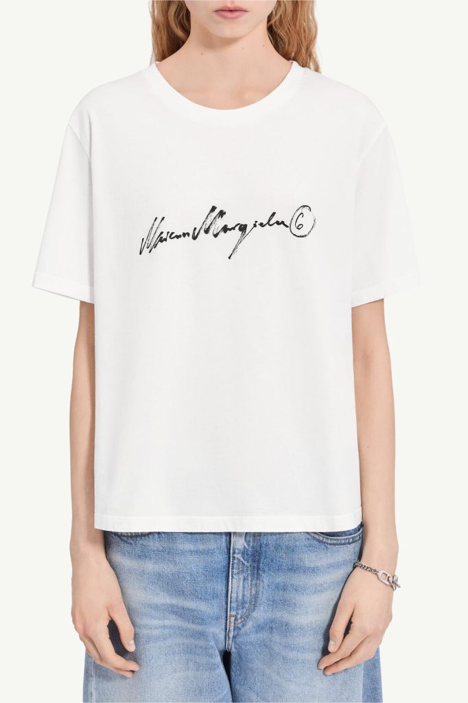 White short-sleeve crew-neck T-shirt with a black cursive logo across the chest and a circled 6 on the right side.