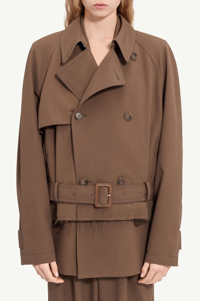 Brown belted trench coat with wide lapels, double-breasted buttons, and a frayed hem detail at the waist.