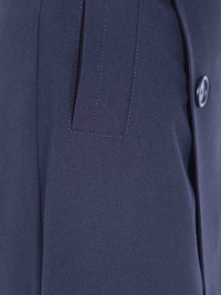 Close-up of a navy blazer showing a pocket flap and a dark button.