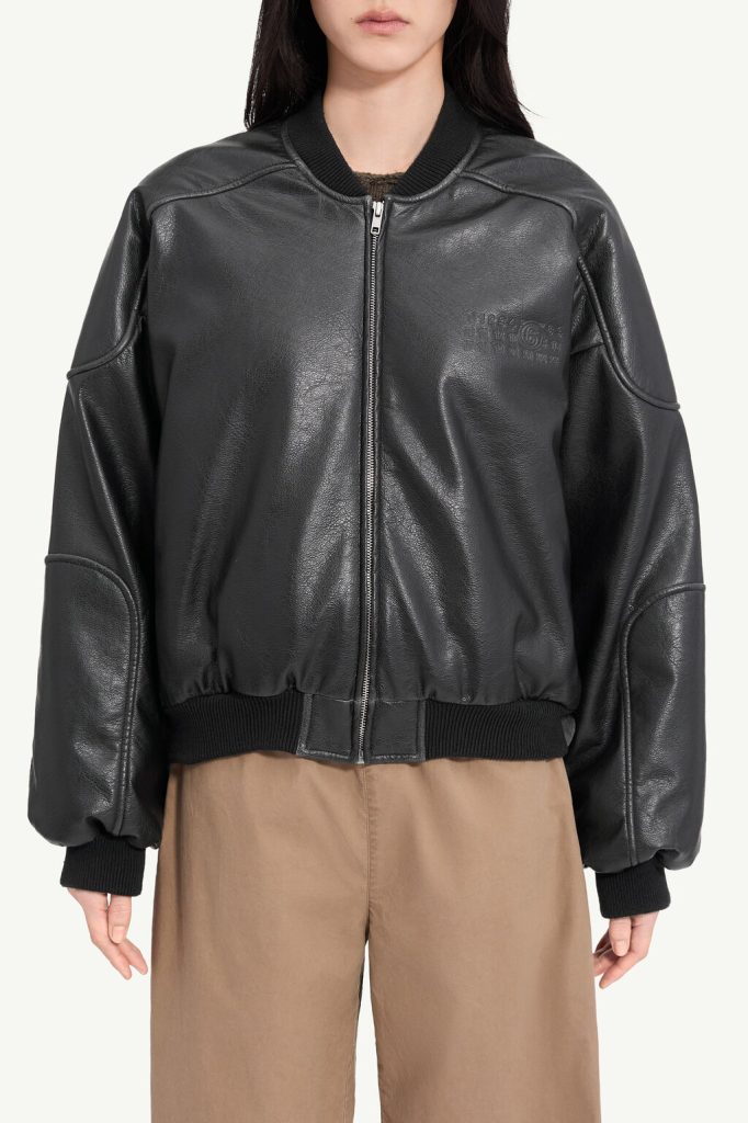 Person wearing a black leather bomber jacket with a front zipper and ribbed cuffs and hem.