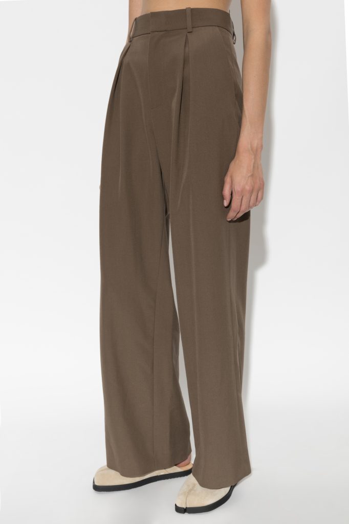 Brown high-waisted, wide-leg trousers with front pleats and belt loops, paired with beige loafers.