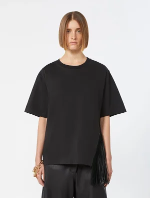 Woman standing in an oversized black T-shirt with a fringe handbag draped at her side, neutral studio background.
