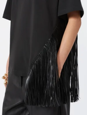 Black fringe handbag slung under the arm with long leather fringe detailing visible beside a black outfit.