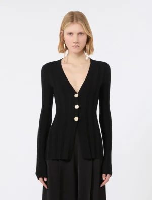 Woman wearing a black ribbed cardigan with a deep V-neck and three gold buttons.