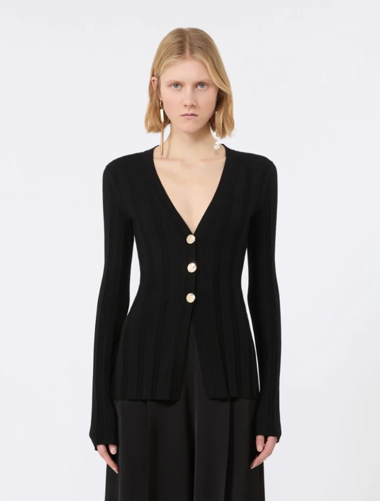 Woman wearing a black ribbed cardigan with a deep V-neck and three gold buttons.