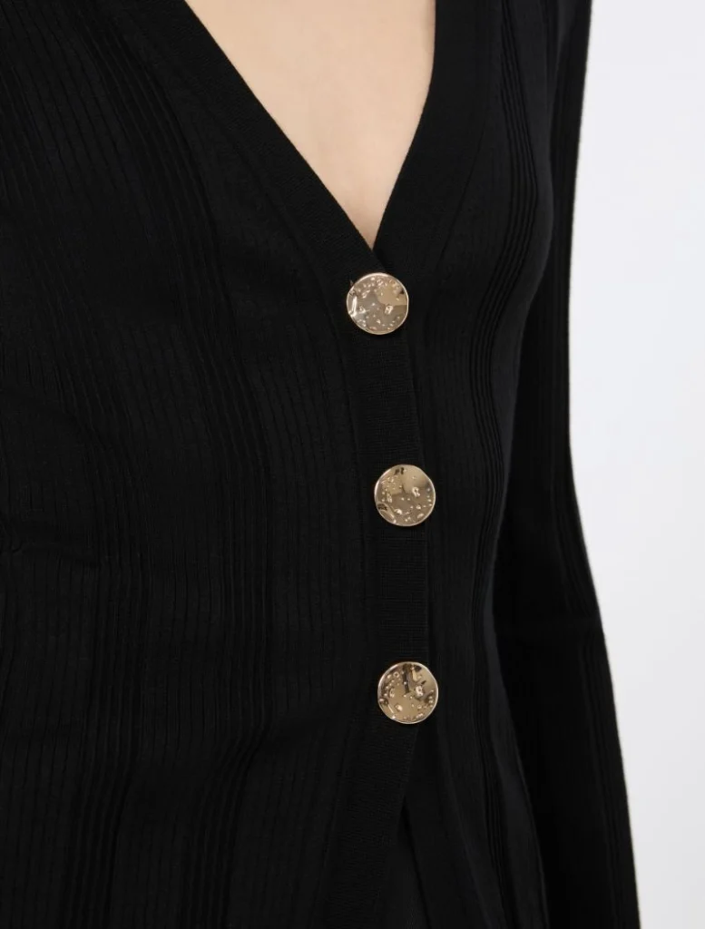 Close-up of a black ribbed cardigan with three gold buttons along the V-neck placket.