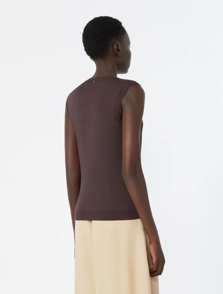 Back view of a person wearing a brown sleeveless knit top and beige skirt