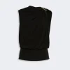 Black draped one-shoulder top with a gold shoulder clasp and ruched detailing, viewed from the back branch of the garment in a studio setting.
